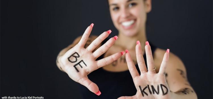 Smiling teacher has be kind written on palms of hand