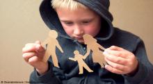 Small boy holds broken paper cutout family